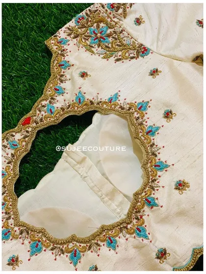 The back of the cream blouse, featuring a deep cutout with a scalloped edge. The entire back neckline is framed with the same beautiful turquoise and red floral embroidery.