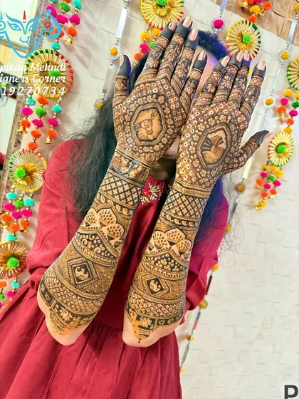 A happy bride hiding behind her beautifully done hands. This traditional design features a dhol and kalash, symbols of celebration and auspiciousness, perfect for a wedding.