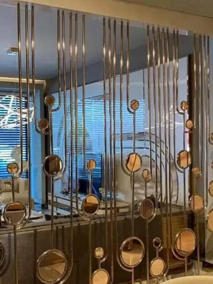 A modern partition made of vertical stainless steel rods and circular mirrored elements. This design creates a sense of separation while reflecting light and adding a touch of glamour.