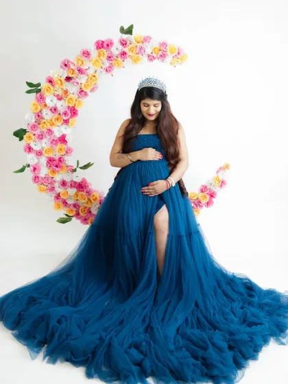 Over the moon for her baby. This creative portrait features a beautiful floral moon prop, with the mom-to-be looking regal in a deep blue tulle gown.