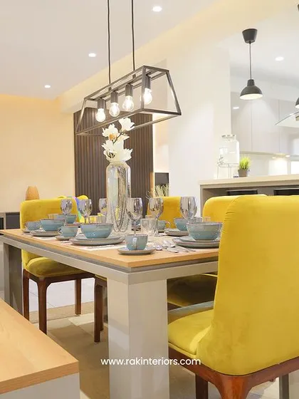 An open-plan dining and kitchen area perfect for modern living. The dining table with a bench and bright yellow chairs creates a cheerful and informal atmosphere for family meals.