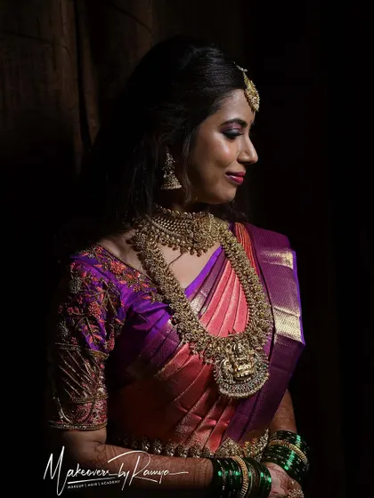 A dramatic, low-key portrait of Santhoshi, where the lighting beautifully highlights her features and the intricate details of her jewelry.
