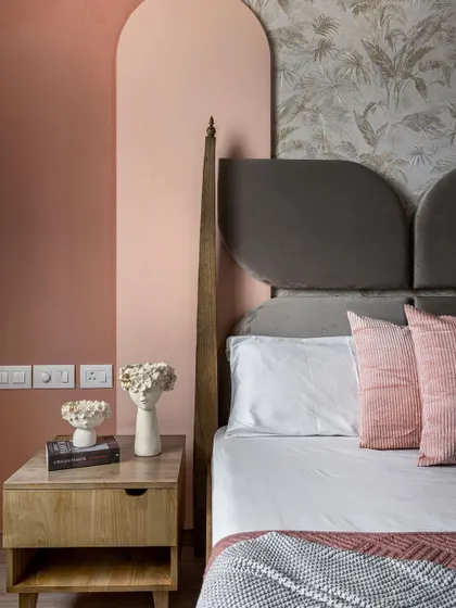 Another detail from the daughter's room, this shot shows the bedside table and the interplay of colors and textures. The arched pink wall panels, botanical wallpaper, and wooden furniture come together to create a space that is rich in detail and personality.