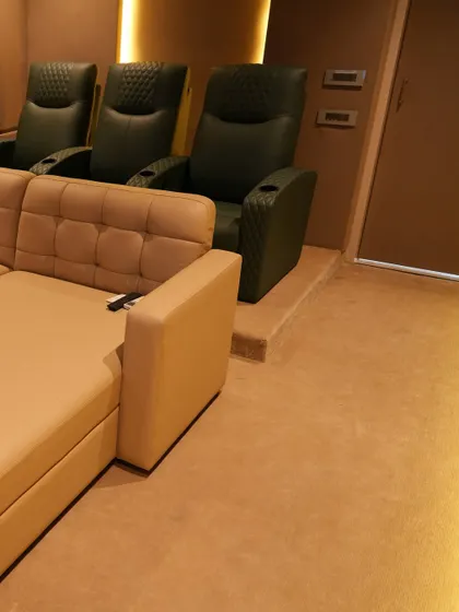 This shot shows the combination of a comfortable daybed in the front and premium, dark green leather recliners in the back, offering flexible seating options for this Nellore home.