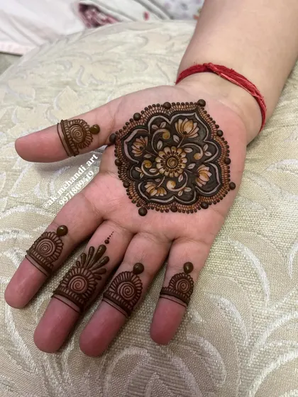 A delicate floral mandala for Karwachauth. The shading gives it a 3D effect, and the simple finger designs complete the look.