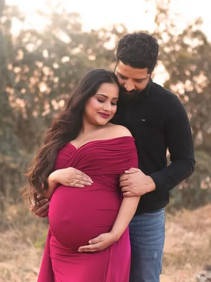 An intimate outdoor couple's portrait captured in the soft evening light. The rich color of her gown contrasts beautifully with the natural background, creating a romantic and moody frame.