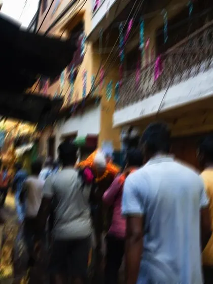A motion-blurred shot of a funeral procession moving quickly through a narrow lane. This technique is used to convey the sense of movement and urgency in the final journey.