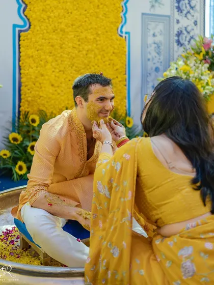 A sister or friend lovingly applies haldi to the groom.