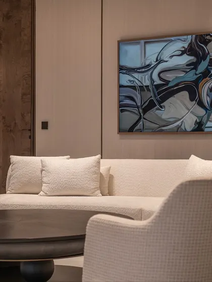 A seating area from our DLF Camellias project, featuring a custom curved sofa and chairs in a neutral fabric. The abstract art on the wall adds a dynamic element to the serene space.