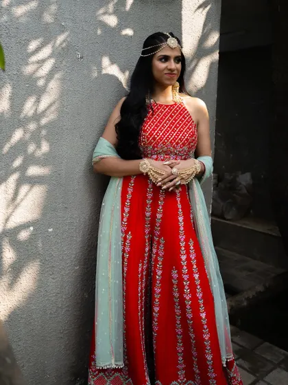 A full-length shot of the bride's Mehendi outfit, a vibrant red jumpsuit.
