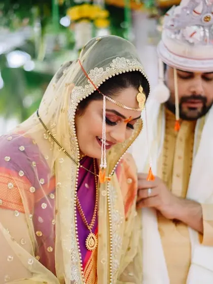 A candid moment during the pheras. The groom adjusts his attire while the bride smiles, a small, real life interaction amidst the grand ceremony.