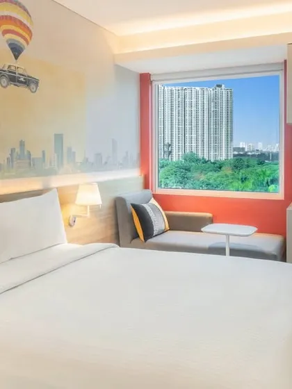 A guest room at the Ibis Hotel in Thane, where modern, efficient design is enhanced by a custom wall mural depicting the Mumbai cityscape, reflecting our approach of infusing local culture into our interiors.