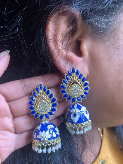 These grand blue Meenakari jhumkas feature a peacock-feather style stud with stone work and a beautifully painted floral dome. A true statement piece.