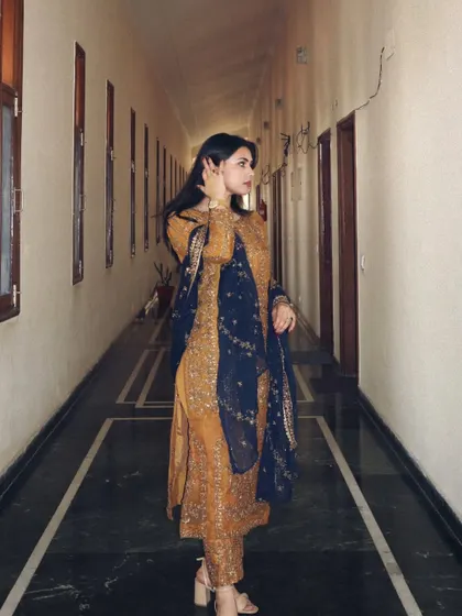 Modeling a stunning, heavily embroidered brown and navy ethnic suit from designer Asim Jofa.