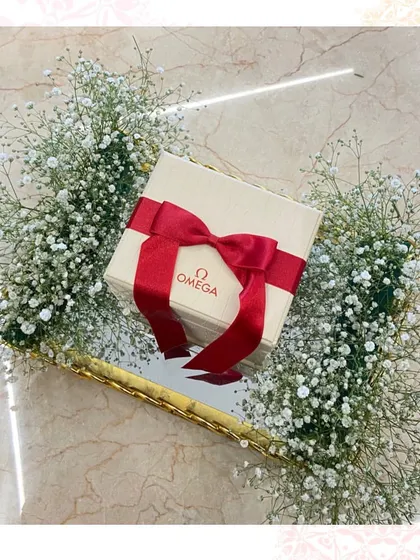 A timeless gift presented beautifully. This Omega watch box is nestled in a bed of baby's breath on a mirror tray, creating a simple yet incredibly luxurious trousseau piece.