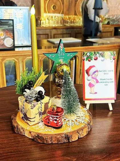A festive Christmas-themed centerpiece with a mini tree, a personalized star, and other holiday trinkets on a wood slice.