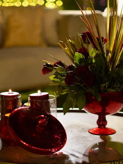 Each detail on this tabletop contributes to the elegant and illuminating vibes. The red glass candle holders and a matching vase with red roses create a passionate and royal mood.