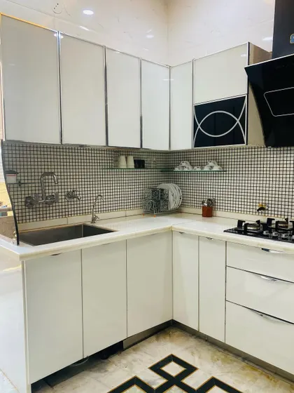 This angle of the black and white kitchen shows the sink area and the high-gloss finish of the cabinets, which helps to reflect light and make the space feel bigger.