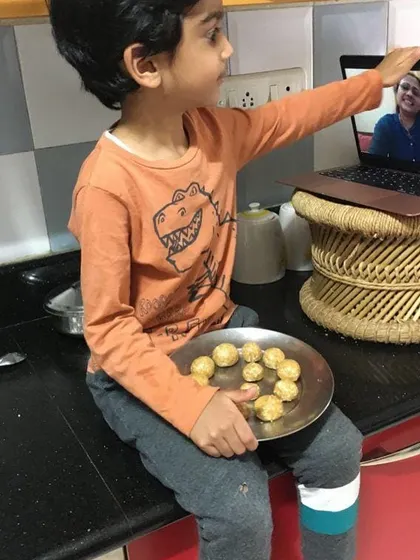 Learning extends beyond the classroom walls. Here, a child connects with his guide and classmates over a video call to share the laddoos he made, blending technology with timeless hands-on learning.
