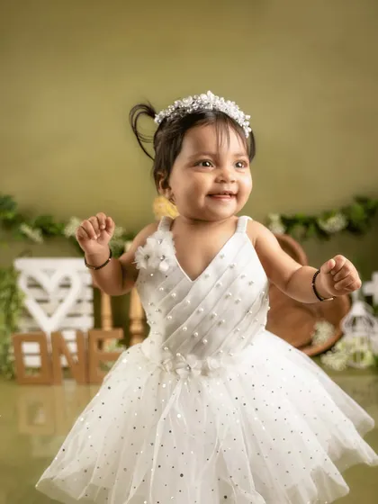 A princess in white. This little girl is a vision of joy in her beautiful dress and tiara for her first birthday portraits.