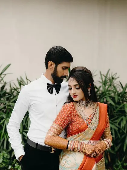 A stylish portrait of a couple dressed for their reception. The groom's classic bow tie and the bride's beautiful saree create a timeless and elegant look.