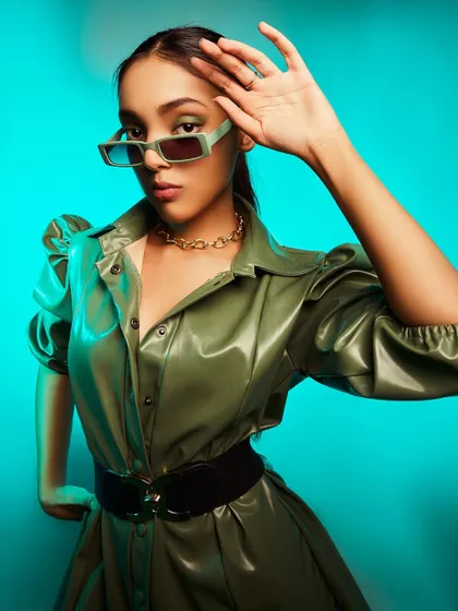 A high-fashion look featuring a green leather jacket and statement sunglasses. I used a vibrant aqua-colored background to make the olive green pop, creating a modern and edgy fashion portrait.
