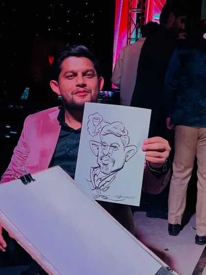 A guest in a stylish pink jacket holding his caricature, which includes a fun detail of a drink. It's all about personality.