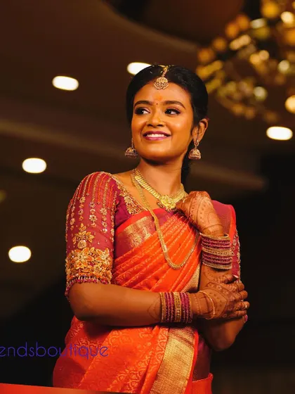 A happy client on her engagement day. She is wearing a beautiful orange silk saree with a custom-designed blouse featuring organza puff sleeves and delicate embroidery.