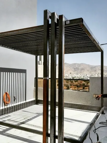 A behind-the-scenes look at the raw metal framework of a large pergola during construction. This shows the sturdy, welded-steel structure before the finishing materials are applied.