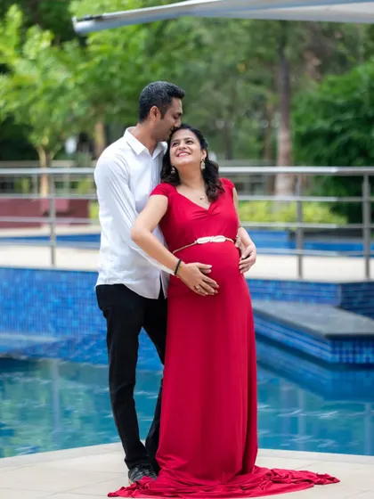 A romantic poolside portrait of an expecting couple. The dad-to-be's gentle kiss on her forehead perfectly captures their love and anticipation.