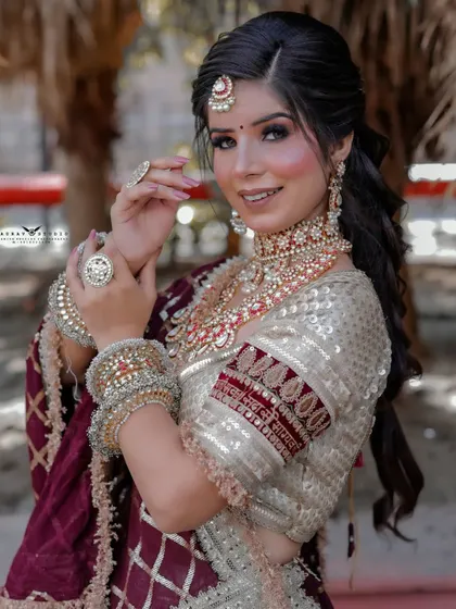 A close-up portrait of the bride in her off-white and maroon ensemble. The focus is on her happy expression and the intricate details of her jewellery.