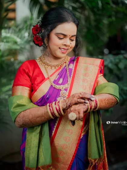 The bride looks down at her hands, adorned with intricate henna. This shot focuses on the traditional details and her serene expression during her engagement day.