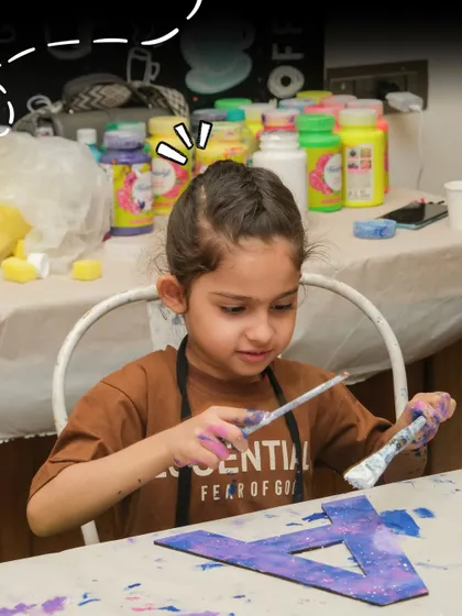 A young girl is deep in concentration as she paints a wooden letter, a popular activity at my kids' art parties.