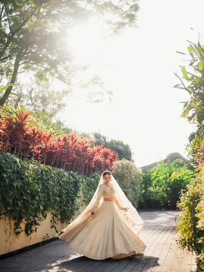 The bride walking in the golden sunlight, her lehenga and veil flowing beautifully. A perfect, cinematic bridal entry shot.