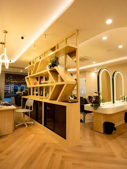 This shot highlights the central partition, which cleverly separates the reception area from the styling stations without closing off the space. The open-shelf design allows for product display while maintaining a light, airy feel.