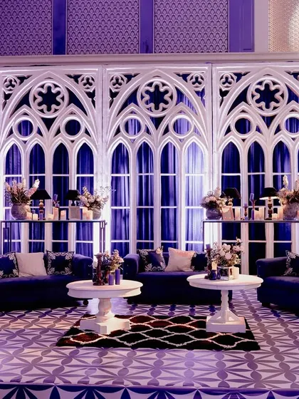 A lounge area set against a backdrop of large, white Gothic arch panels. The deep blue sofas and dramatic lighting created a sophisticated and moody corner for guests to relax.