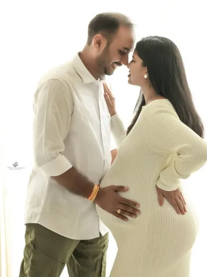 An intimate, high-key portrait against a bright window. This simple and modern style focuses on the couple's connection as they touch foreheads, full of anticipation.