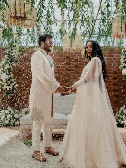 A joyous moment as the couple is showered with petals after their engagement. The hanging floral installations and exposed brick wall create a beautiful, rustic-chic backdrop.