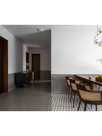 A long view down a corridor, where the polished concrete floor meets a patterned tile section, defining the transition into the dining space.