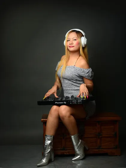 A full-length portrait of a DJ with her equipment. This shows her in her element, creating an authentic image for her professional music profile.