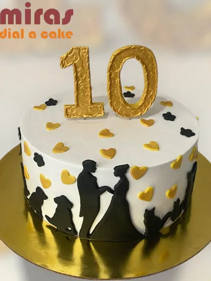 A heartwarming cake celebrating a 10th anniversary, including the furry members of the family. The design features silhouettes of the couple with their pets, surrounded by gold and black hearts.