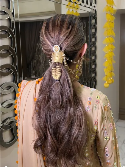 A textured ponytail with a unique, woven hair accessory. This style combines the ease of a ponytail with the elegance of detailed craftsmanship, perfect for a festive look.