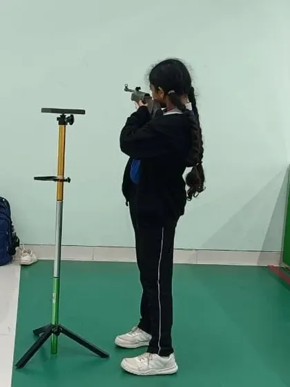 A young student from our Greenwoods High International School program practices her standing position. We work with schools to introduce shooting as a sport that builds focus and character.
