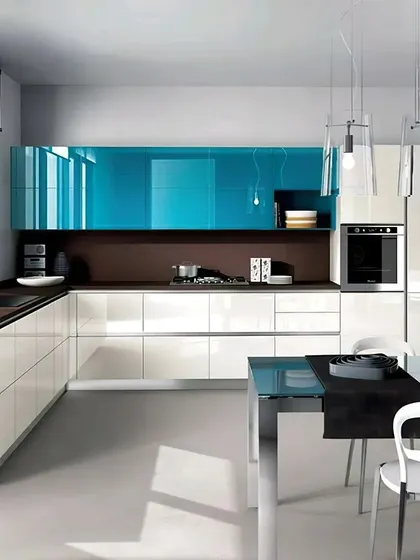 An ultra-modern kitchen and dining space with glossy white and striking blue cabinets. The open layout and glass dining table create a sense of spaciousness, ideal for contemporary apartment living.
