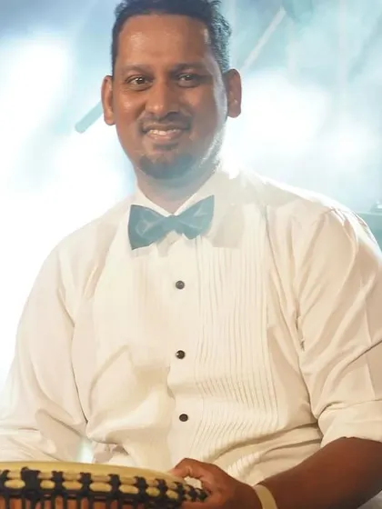 Our percussionist, all smiles during a performance. His skill with instruments like the djembe adds a unique rhythmic flavor to our sound.