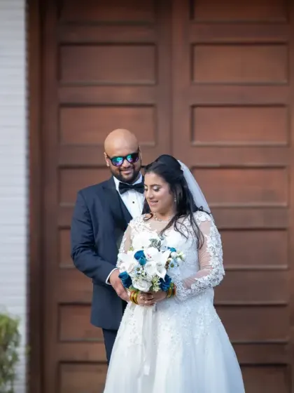 A fun and stylish wedding portrait against a large wooden door. The groom's sunglasses add a touch of cool to this happy couple's photo.