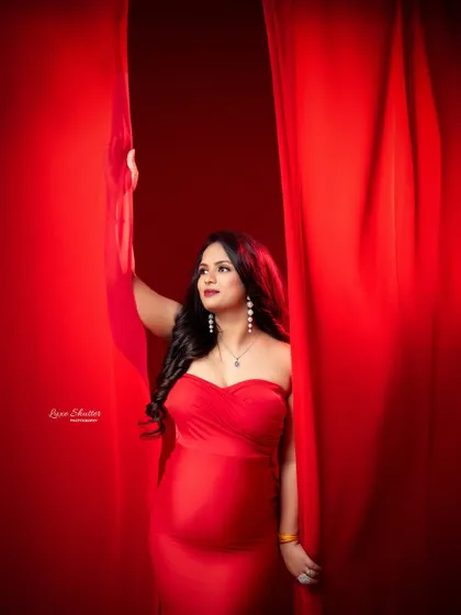 Peeking through the curtains, this shot has a lovely, intimate feel. The rich red fabric envelops the mother-to-be, creating a warm and dramatic mood.