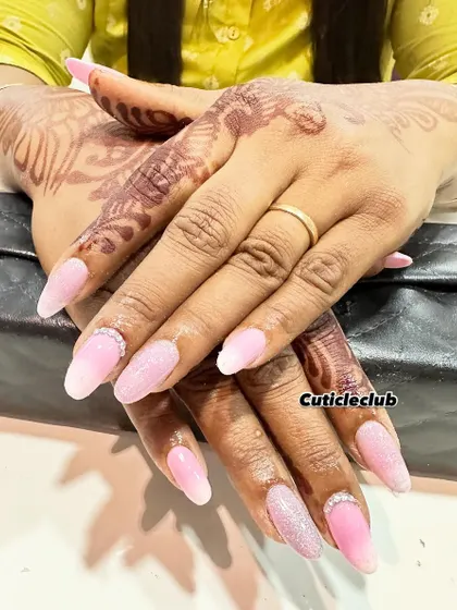 A soft and romantic look featuring a baby pink ombre with a sugar glitter effect. A simple rhinestone detail at the cuticle adds a touch of elegance, making it perfect for an engagement.