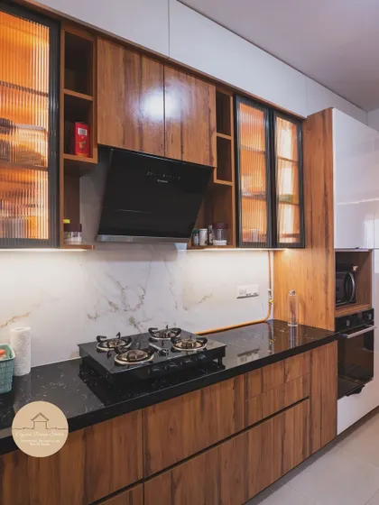 A closer look at the Godrej Air Hoodi kitchen. This view highlights the built-in oven and microwave unit, the sleek handleless drawers, and the combination of wood laminate with glossy white finishes for a clean, contemporary look.