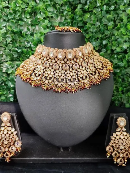 A classic and heavy bridal choker set available for rent. This piece features intricate kundan work with uncut polki stones and comes with large, matching chandelier earrings.